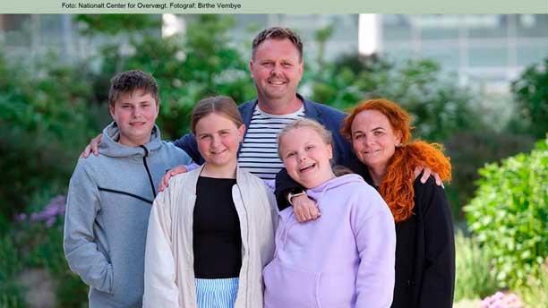 Forsiden af rapporten har et billede af en familie på fem, der alle står tæt sammen og kigger smilende i kameraet.