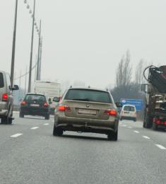 Biler og lastbil ses kørende bagfra i tre spor på motorvej