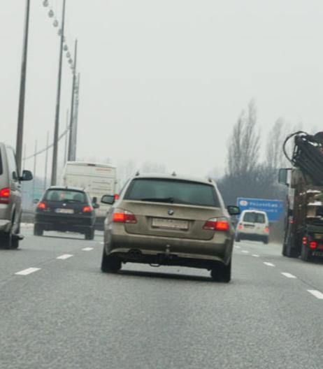 Biler og lastbil ses kørende bagfra i tre spor på motorvej