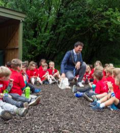 Borgmester Henrik Rasmussen sidder i en stor gruppe af børn, der er ved at spise mad
