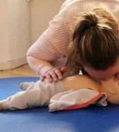 Kvinde udøver førstehjælp på baby-dukke.