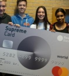 Fem unge mennesker der står med et stort gavekort i hånden