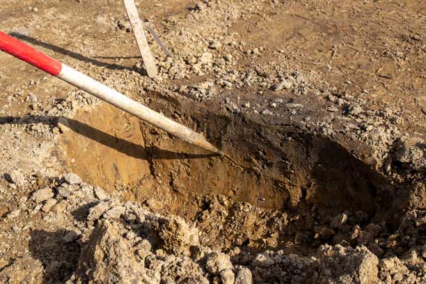 Markeringspind peger et mørkere jordlag ud i et gravet hul