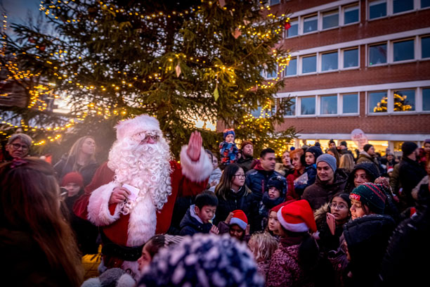 Julemand ved et juletræ og en stor flok mennesker omkring